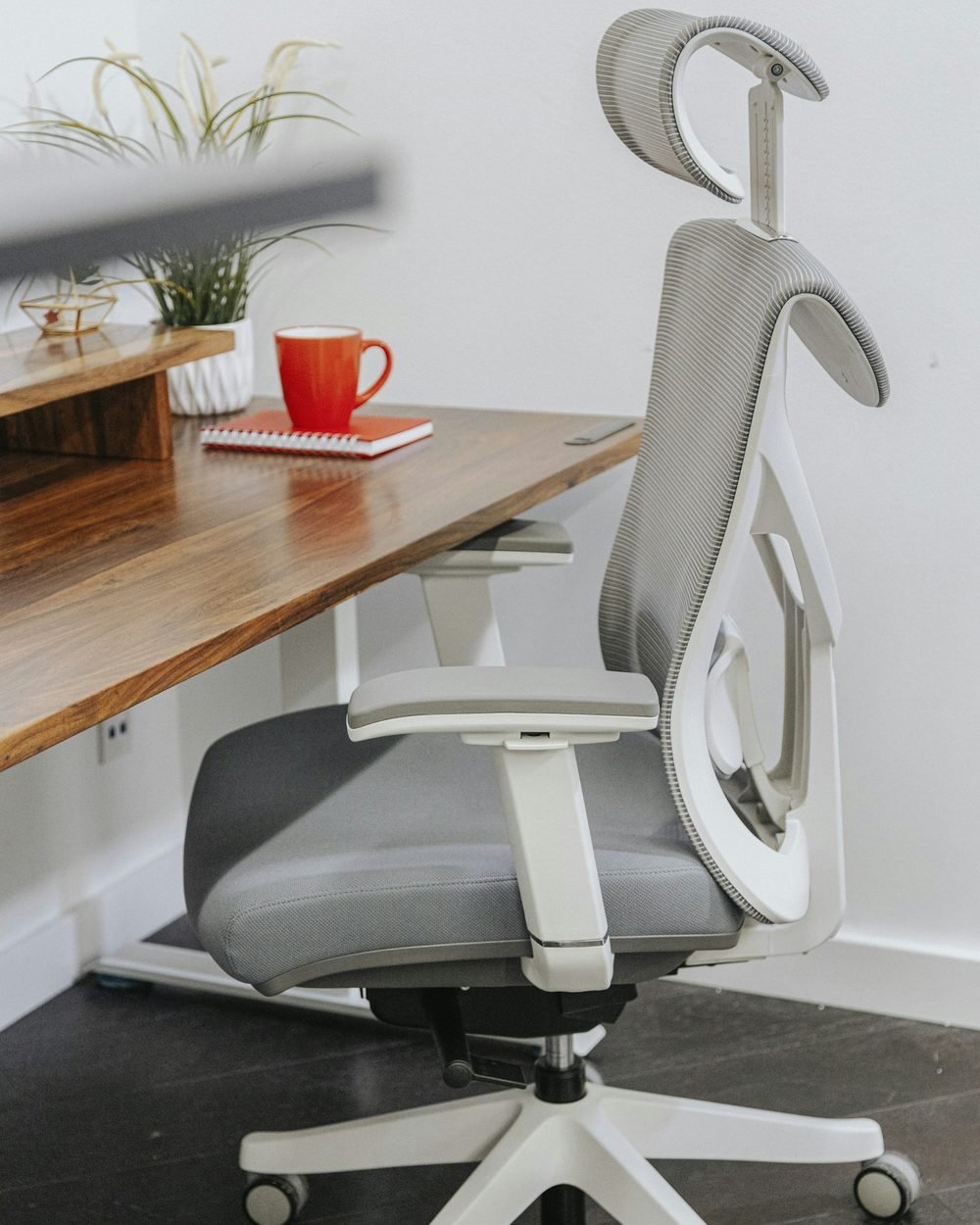 Ergonomic mesh office chair with headrest on a modern wooden desk in a home office